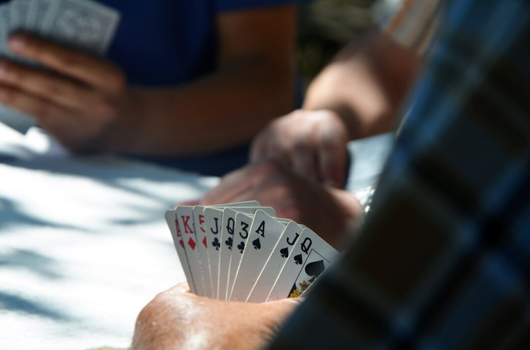 Elderly friends playing cards together at a wooden table in a community hall